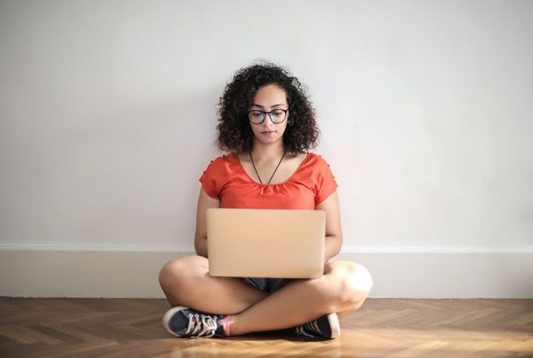 young woman sitting on floor looking at laptop