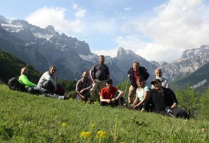 hikers in green field in front of mountains