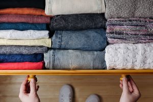 hands pulling open drawer of folded clothes